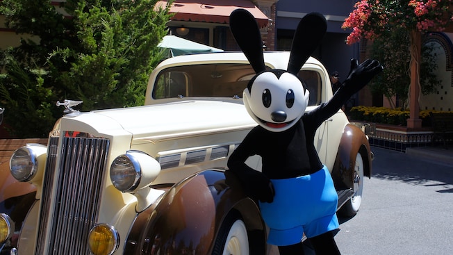 Oswald leaning against a car and waving