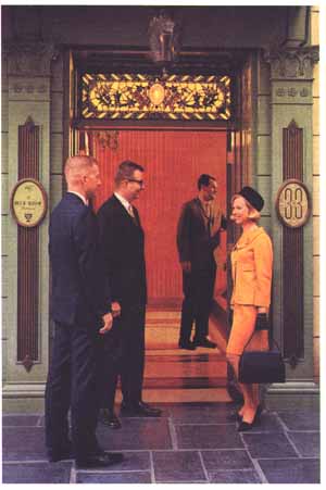 Three guests dressed in fancy clothes stand outside the Club 33 door