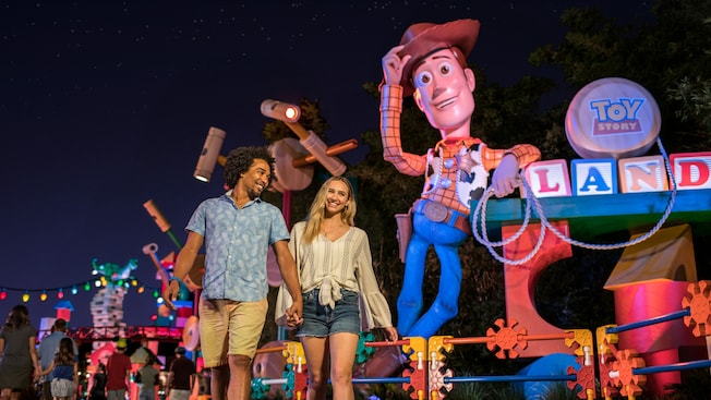 Adults walking in front of the Toy Story land sign