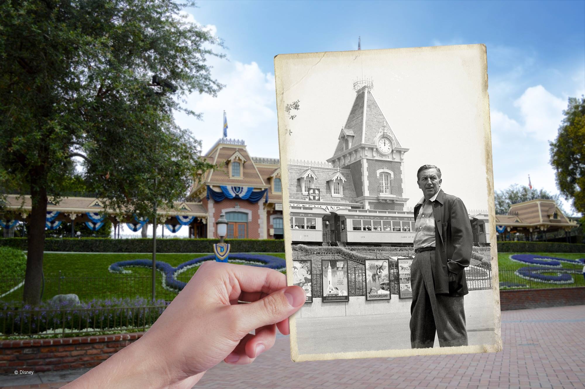 Hand holding a picture of Walt Disney in front of Disneyland