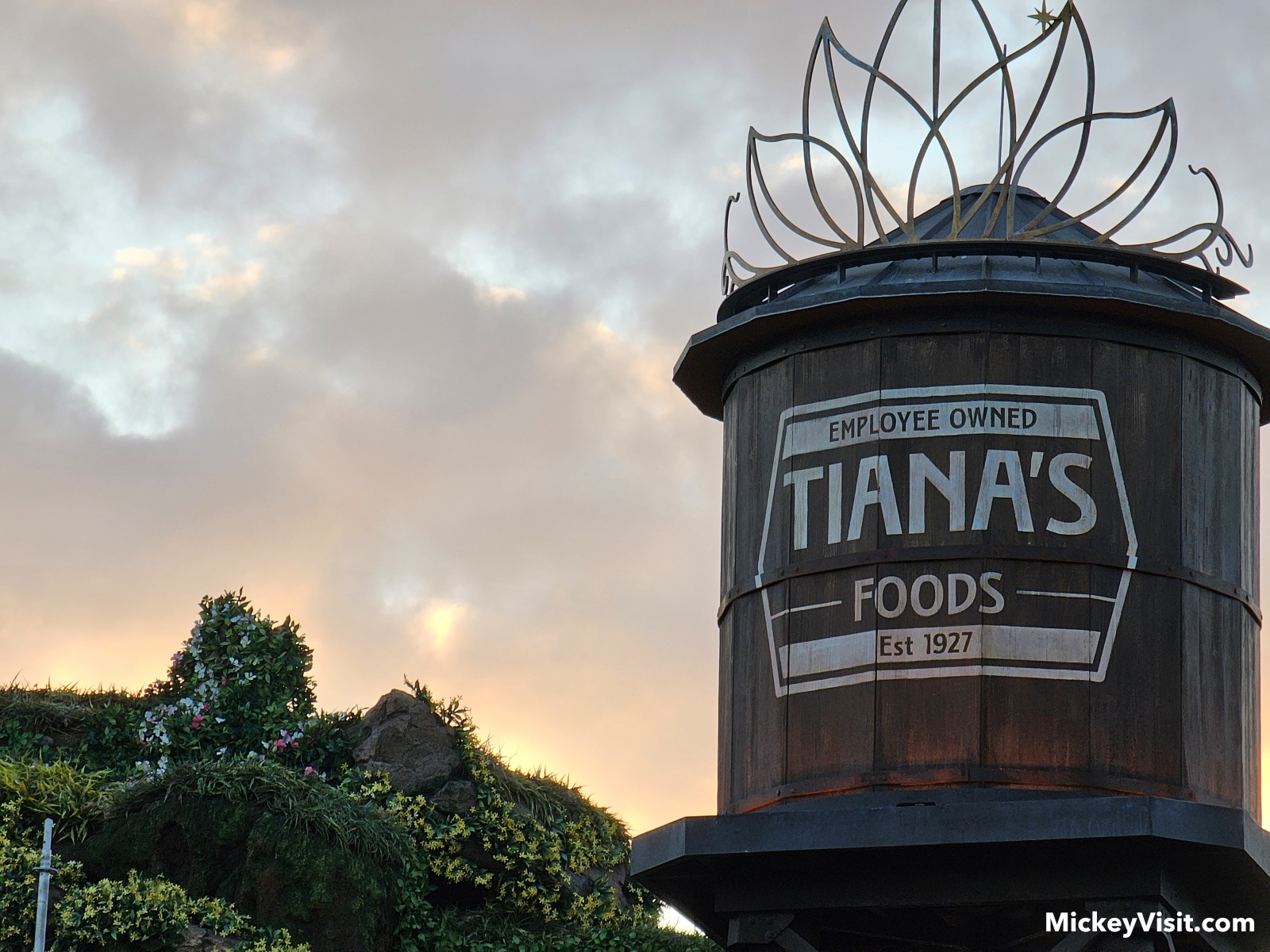 A look at the tiara-topped Tiana's Foods water tower at Tiana's Bayou Adventure as the sun goes down in the background.