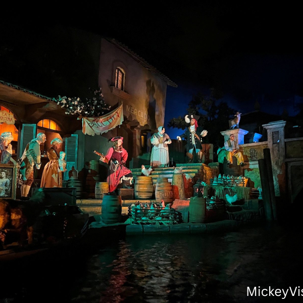 Pirates of the Caribbean scene at Disneyland featuring animatronic prates in a colorful nighttime village setting along the water