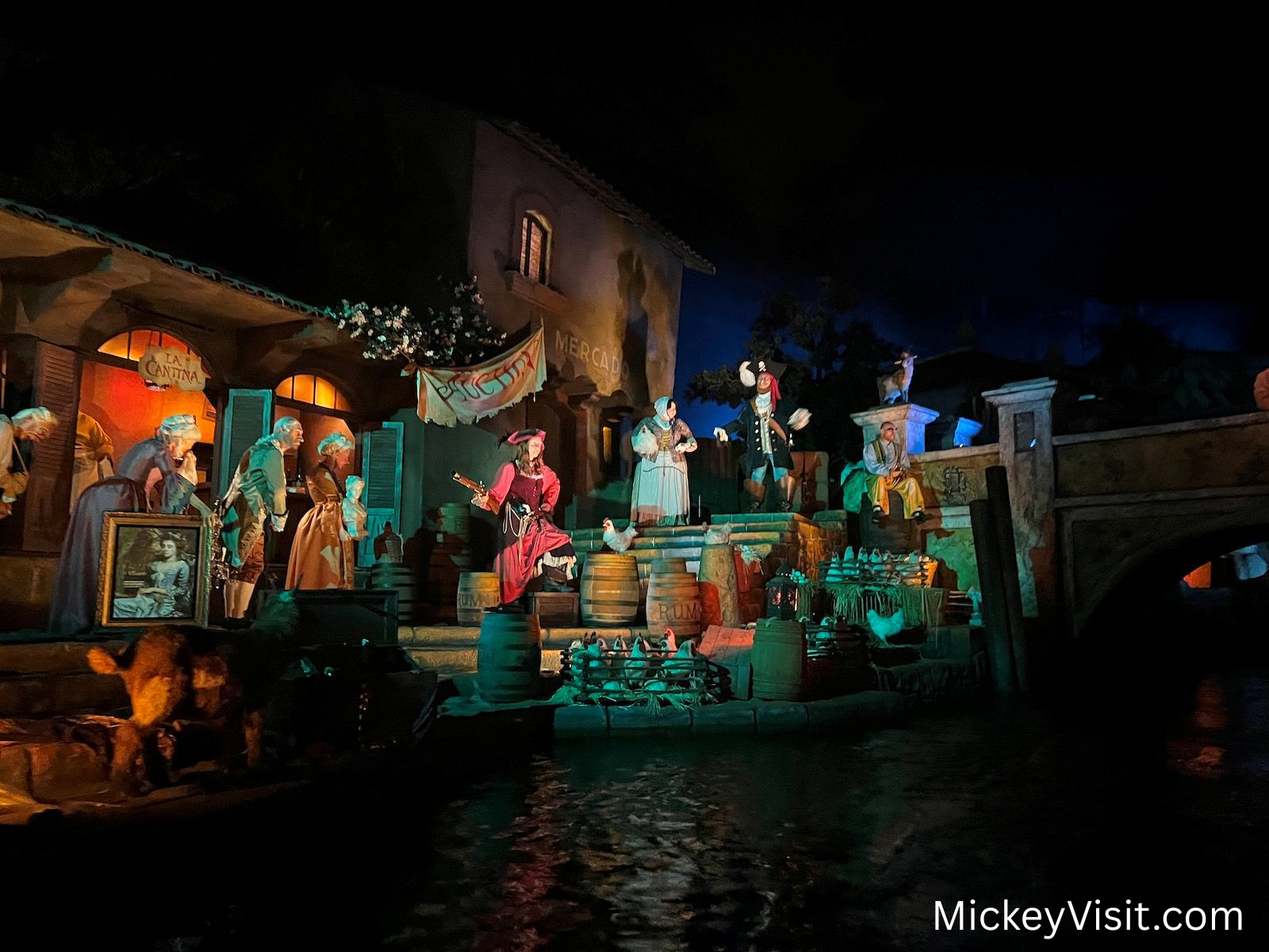 Pirates of the Caribbean scene at Disneyland featuring animatronic prates in a colorful nighttime village setting along the water