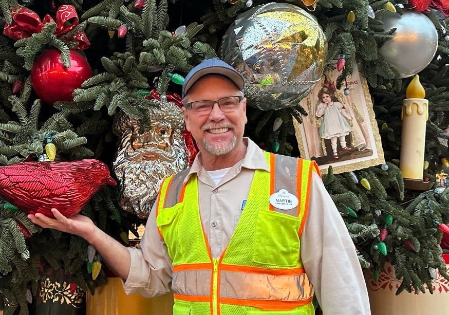 disneyland cast member in front of christmas tree