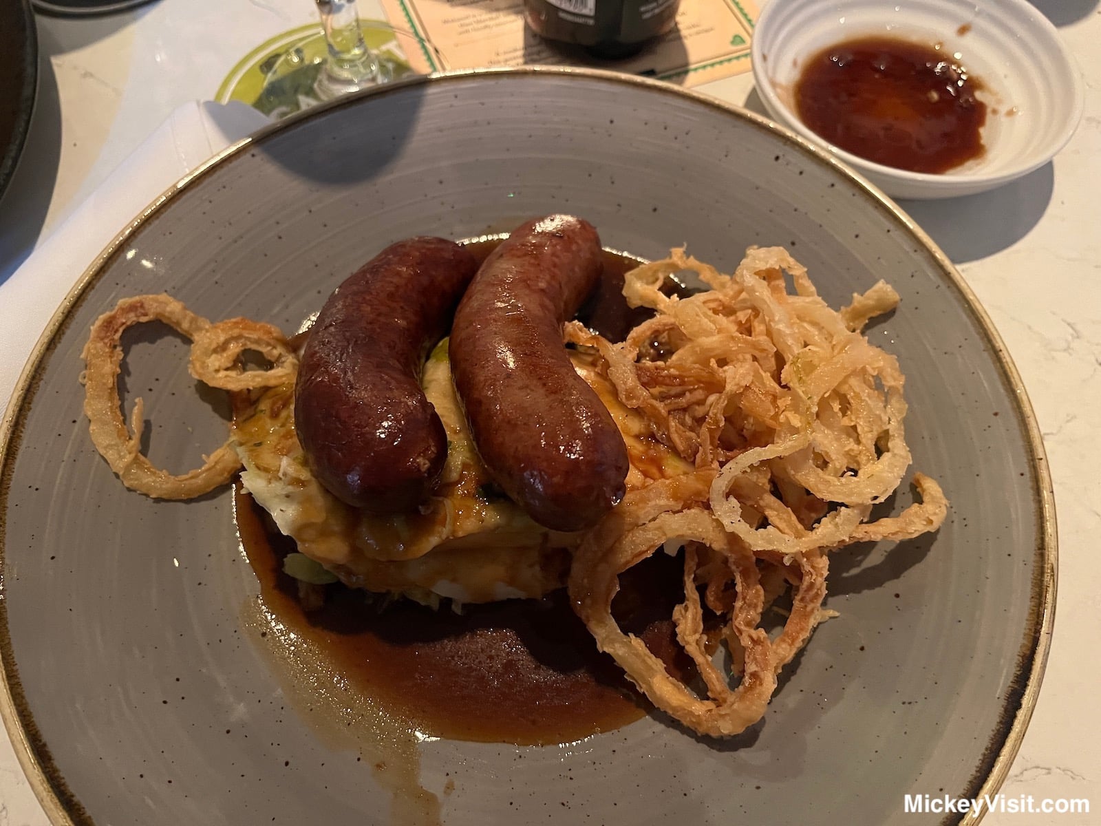 Delicious sausages with mashed potatoes, crispy onions, and red wine jus