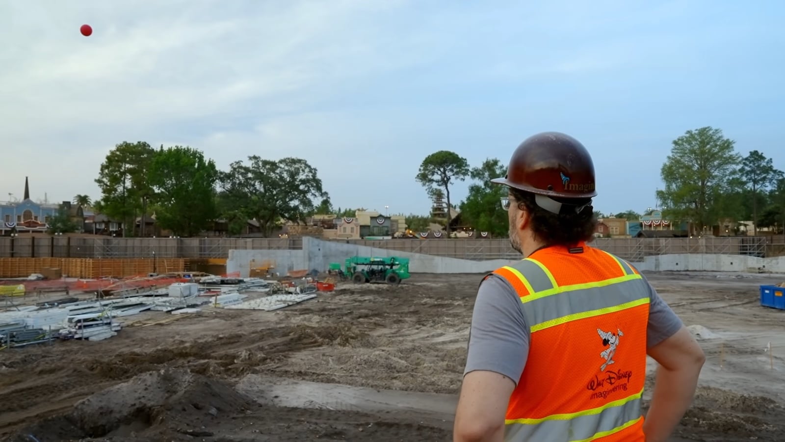 Imagineer in construction vest standing in dirt construction site with balloon high in the sky