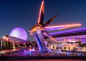 Monorail moving in front of large fake rocketship