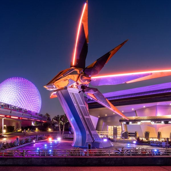 Monorail moving in front of large fake rocketship