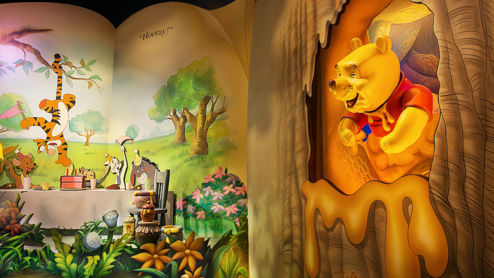 A scene within The Many Adventures of Winnie the Pooh attraction, with a Pooh Bear animatronic sticking out of a bees' nest filled with honey, and the Hundred Acre Woods characters celebrating a birthday in the woods.
